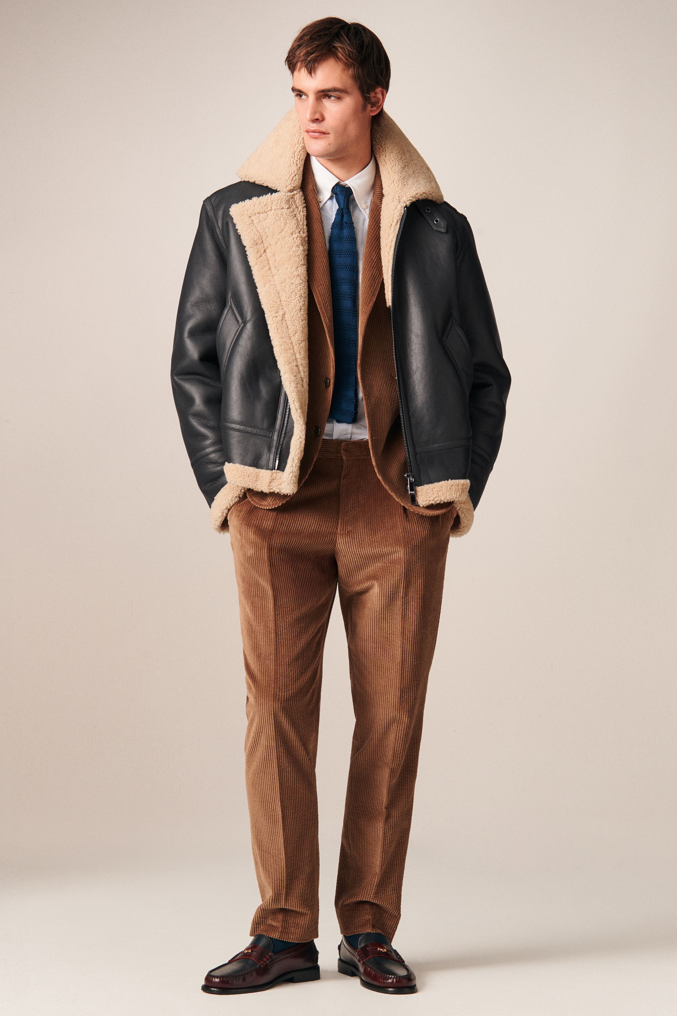 Tommy Hilfiger 26FW 男装回到品牌最擅长的美式学院与都市绅士语境。条纹针织、飞行夹克、羊羔毛外套与双排扣大衣共同勾勒出成熟却不老派的美式精英形象。色彩以海军蓝、酒红、驼色为核心，强化可靠、易穿的商业属性。系列不追求先锋表达，而是精准回应全球市场对“经典升级版”的现实需求-顽石频道趋势研究